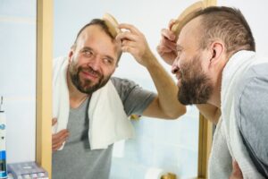 uomo allo specchio che cerca di migliorare aspetto dei capelli